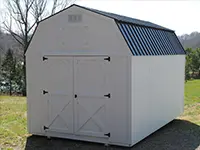 White portable storage building with double barn doors and black metal roof